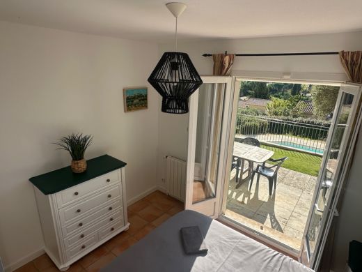 Chambre au rez-de-chaussée avec lit double de 160 cm, armoire intégrée, commode et accès direct à la terrasse, offrant un espace confortable et pratique.