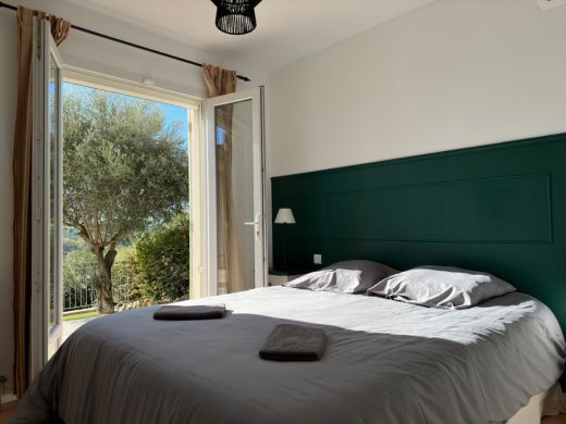 Chambre au rez-de-chaussée avec lit double de 160 cm, armoire intégrée, commode et accès direct à la terrasse, offrant un espace confortable et pratique.